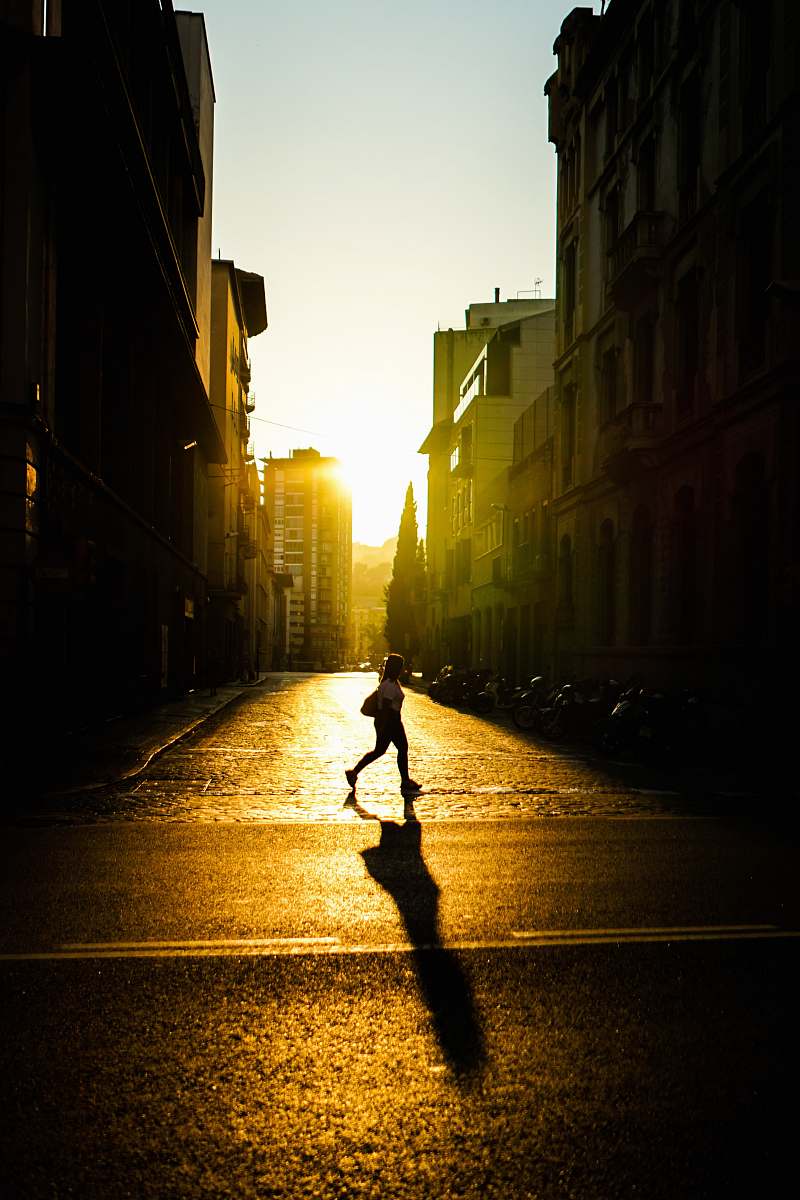 flare person crossing street between buildings light