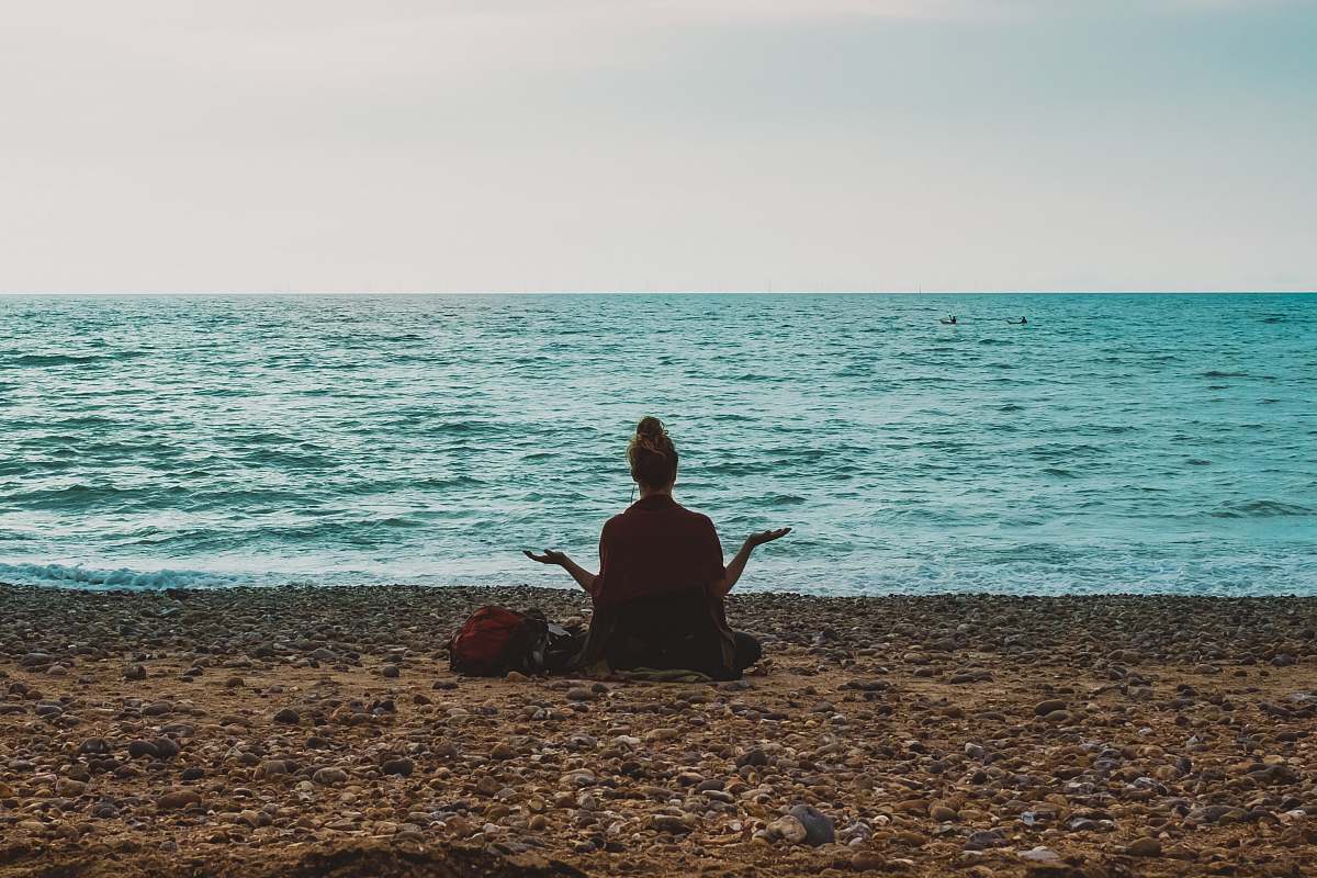 human person doing yoga on seashore during daytime people