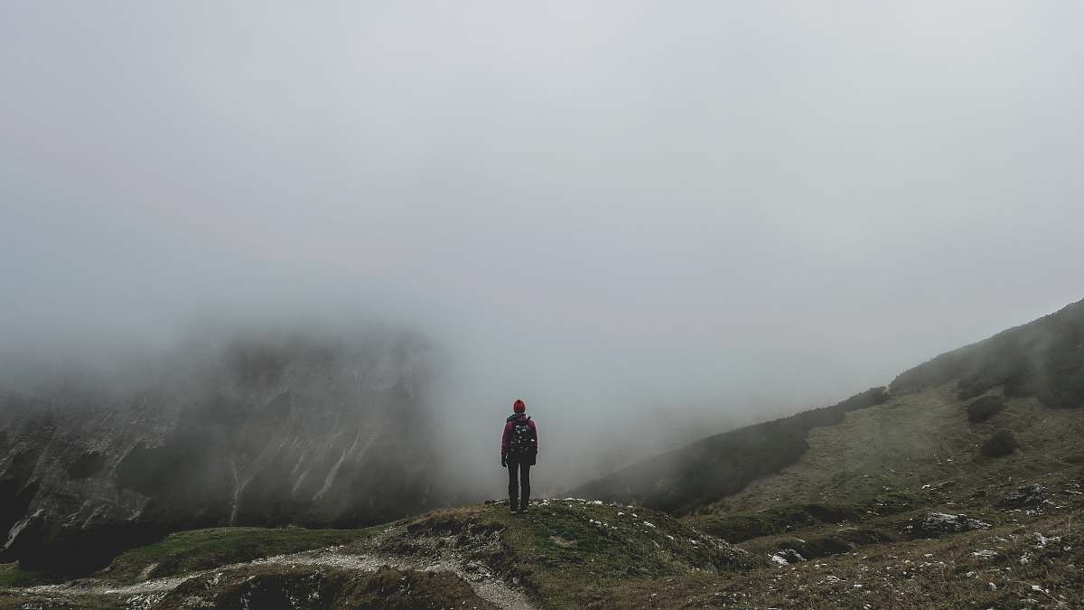grey person standing on green mountain near smoke during daytime austria