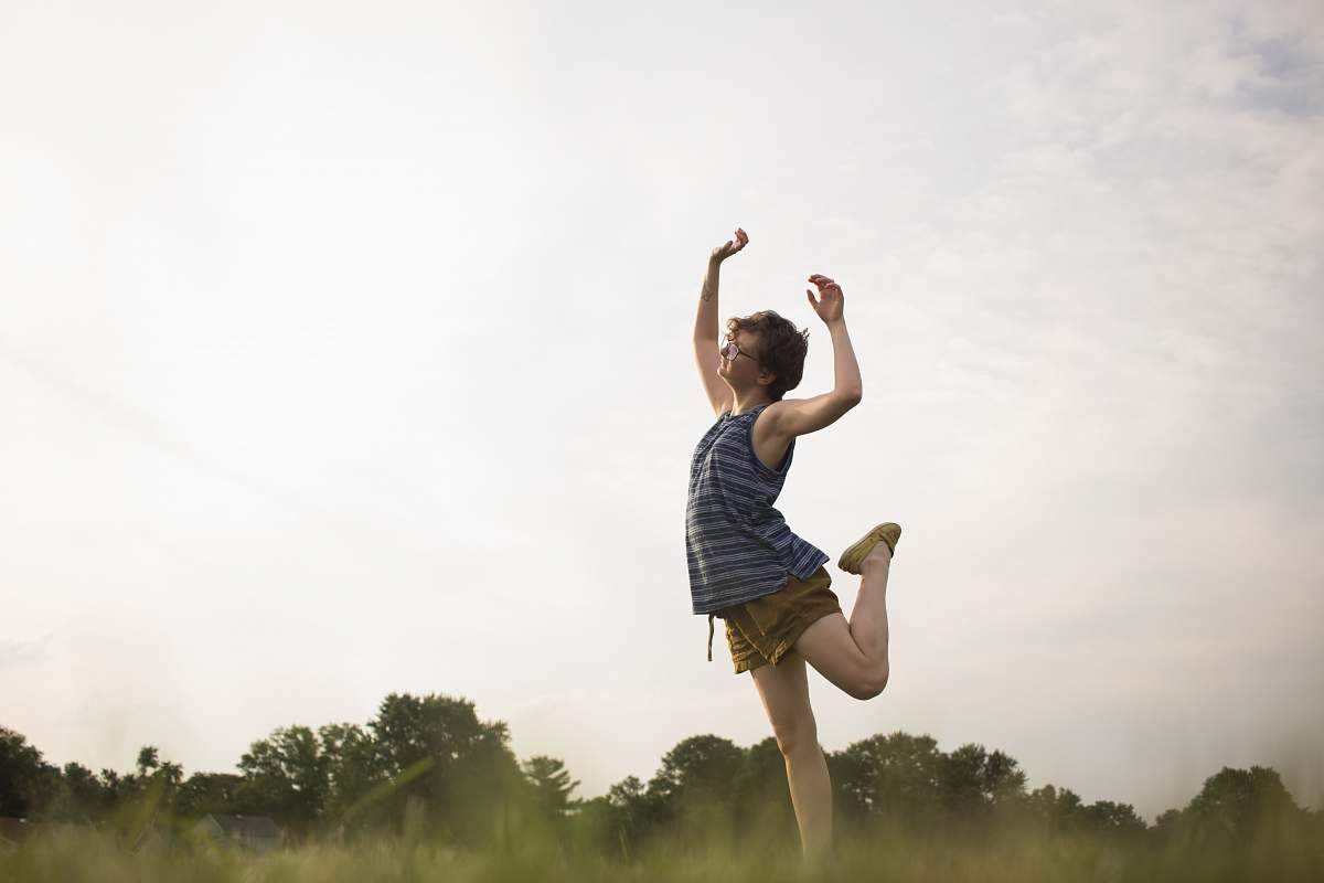 human person standing raising right leg as well as both hands apparel