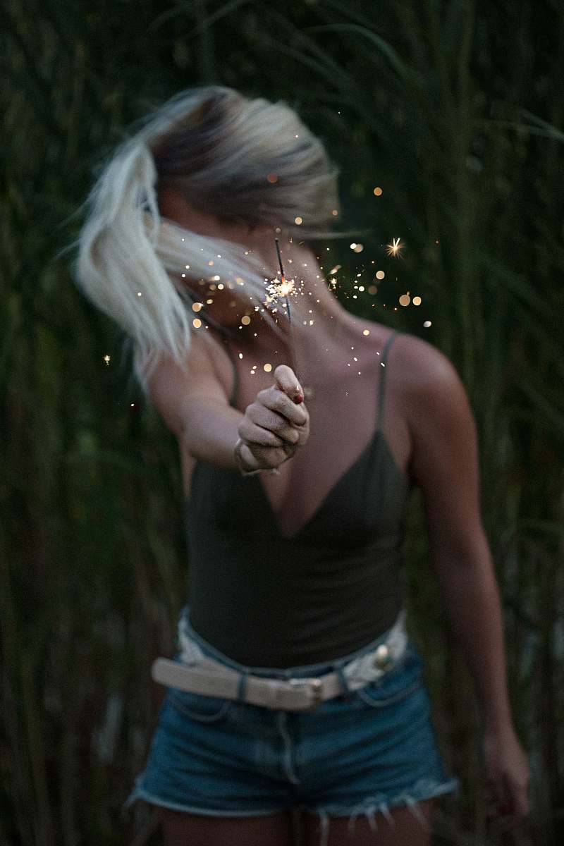 people selective focus photo of woman holding sparkler while looking away girl