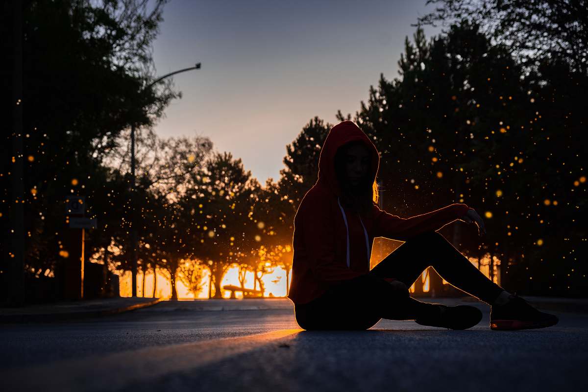 human silhouette of woman sitting on road during golden hour apparel