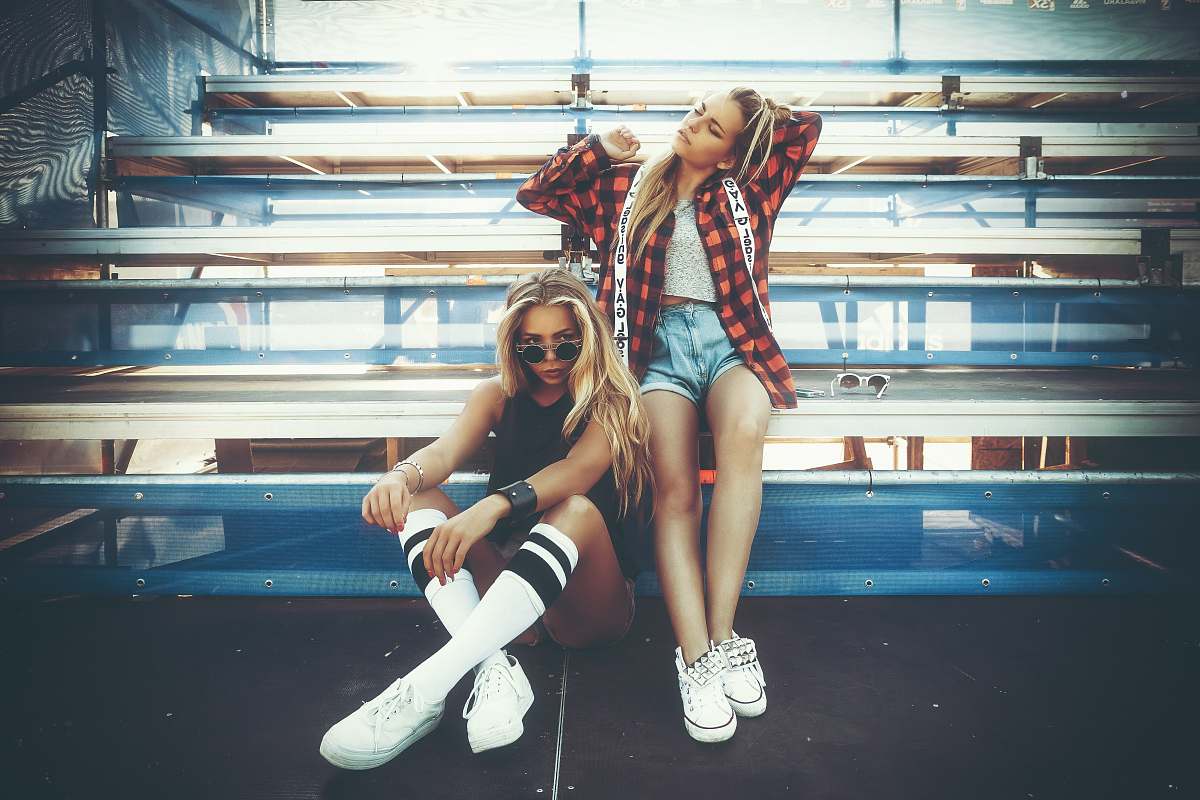human squatting woman beside woman in red and black checked top people