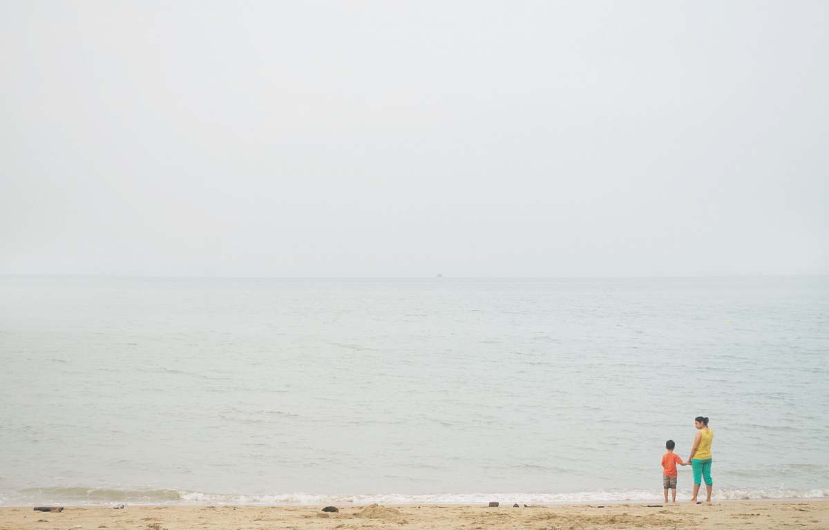 human woman and boy standing on seashore during daytime grey