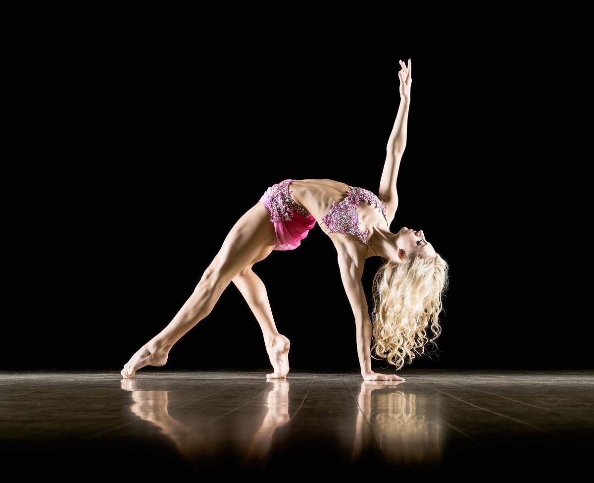 dance woman bending on floor and with black background ballet