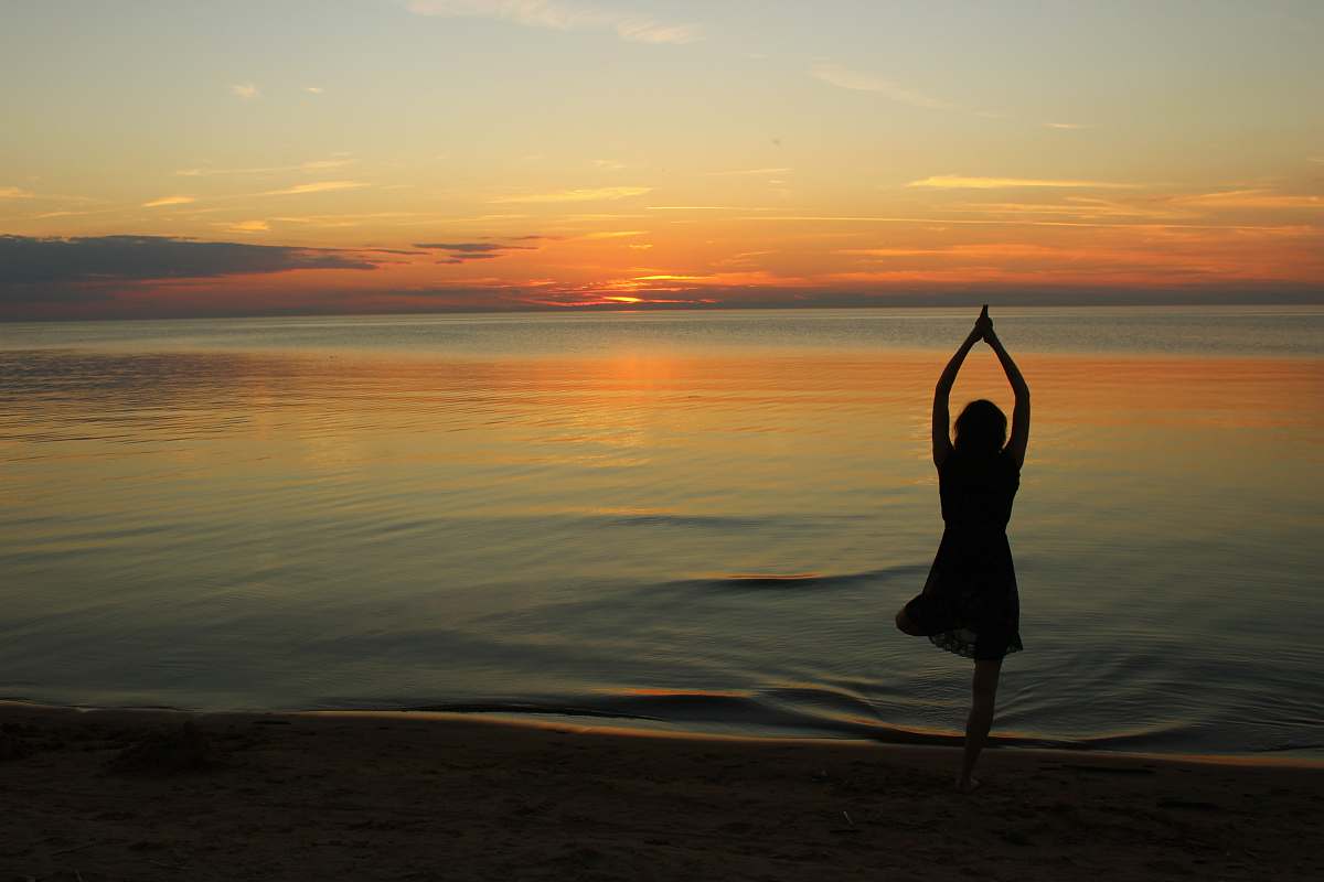 fitness woman doing yoga near calm body of water during golden hour sports