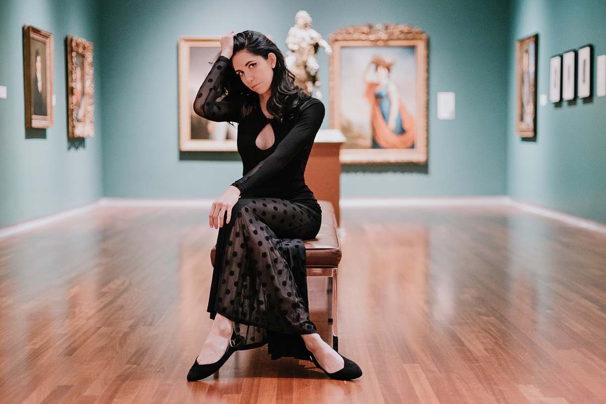 human woman in black long-sleeved dress sitting on bench wood