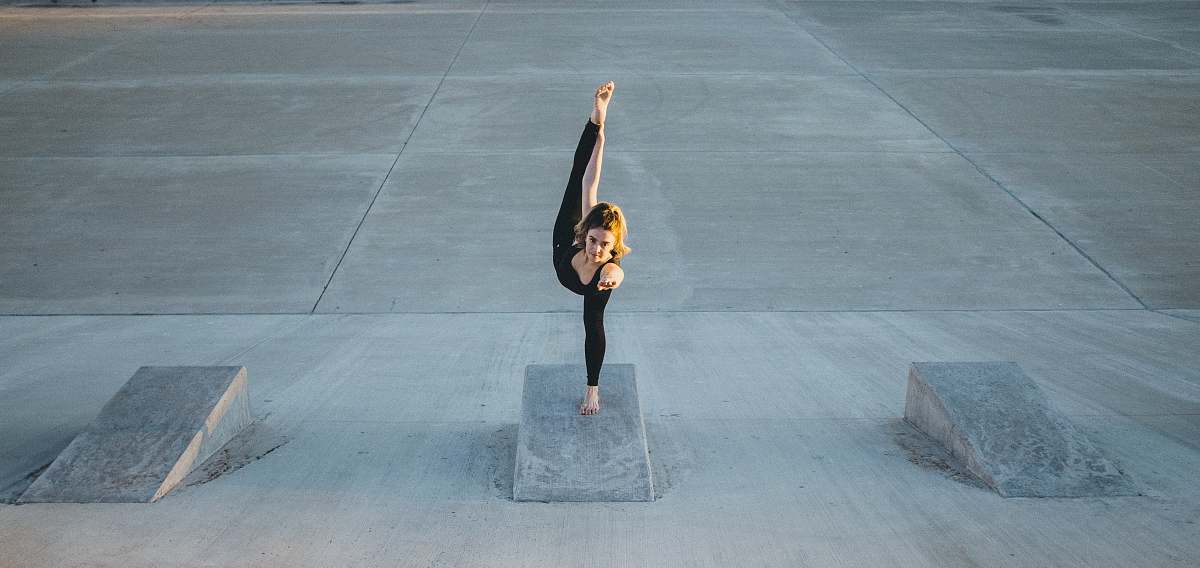 human woman in black sleeveless shirt doing yoga grey