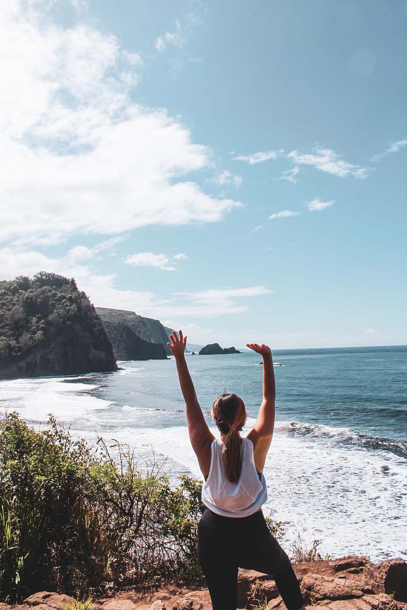 human woman raising both her arms on seashore during day exercise