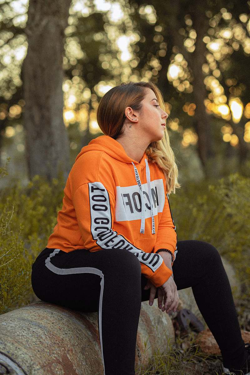 clothing woman sitting on log in over hoodie apparel
