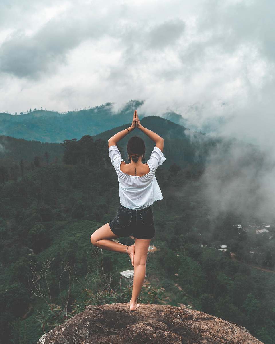 human woman standing on rock facing forest apparel