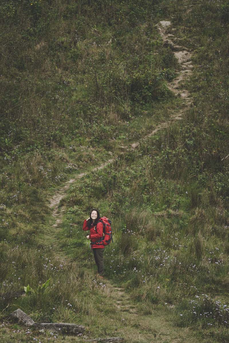 human woman walking on pathway between grass outdoors