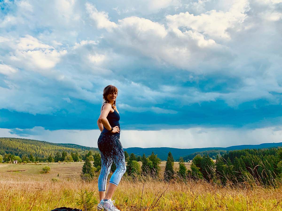 human woman wearing black and teal ju7mp suit walking on grass field apparel