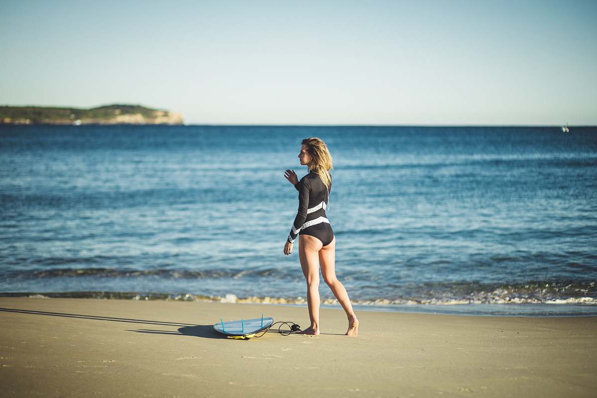 human woman wearing black one-piece swimsuit walking on shore apparel