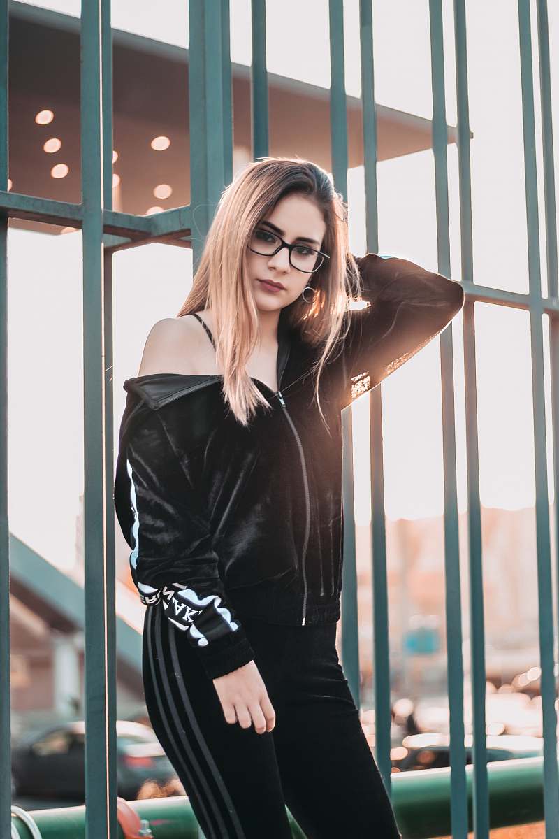 human woman with eyeglasses leaning on green metal frame at daytime people