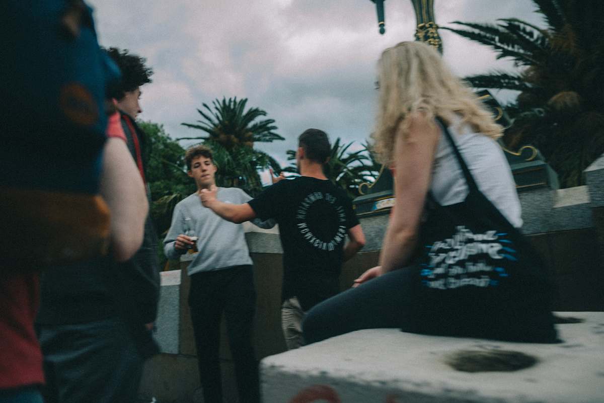 human woman witting on concrete facing men apparel
