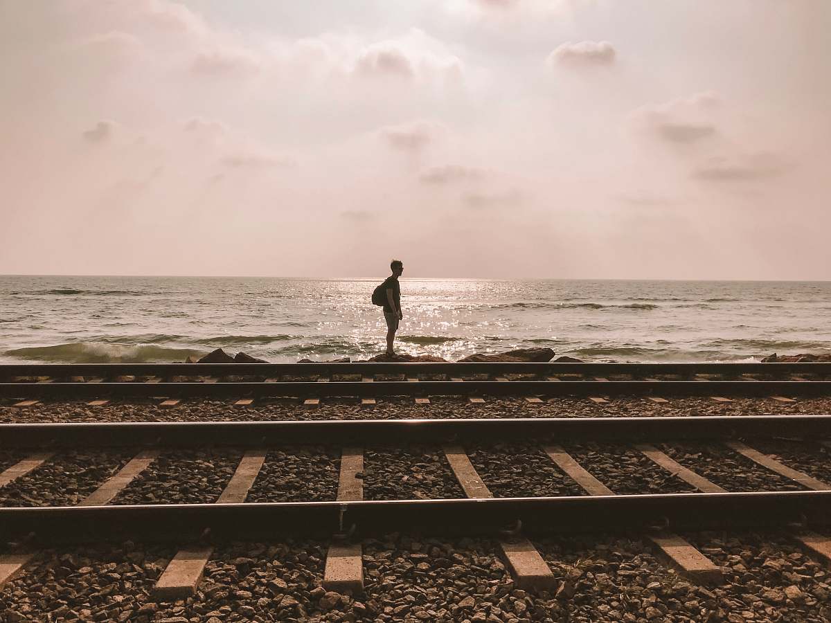 railway boy standing on shore near waves train track