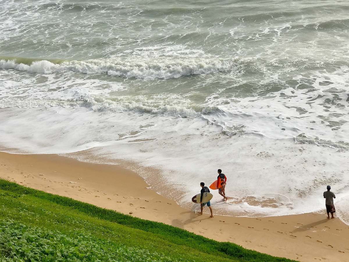 beach two person holding surfing board while walking on seashore at daytime ocean