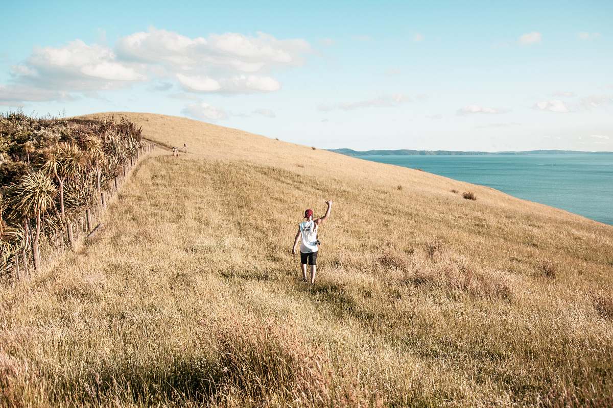 field person standing beside body of water during daytime grassland