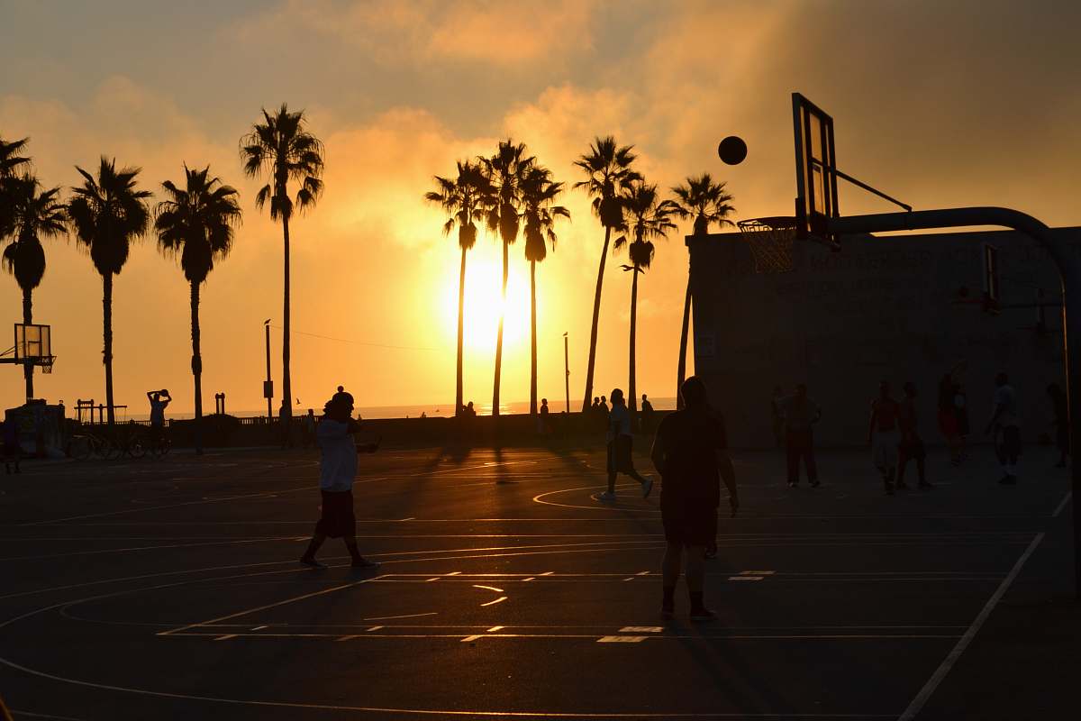sun silhouette photo of people playing basketball during sunset beach