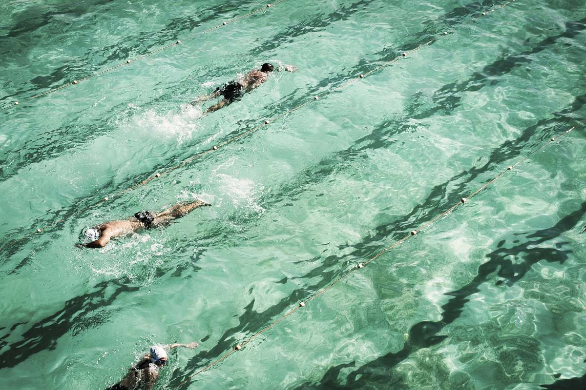 person three men swimming in swimming pool swimming