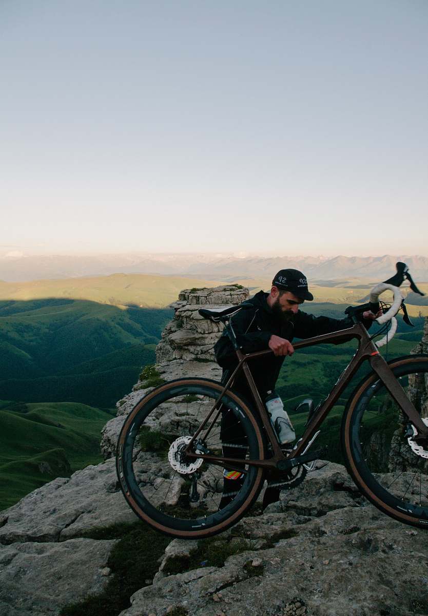 machine man carrying road bike at top of mountain bicycle