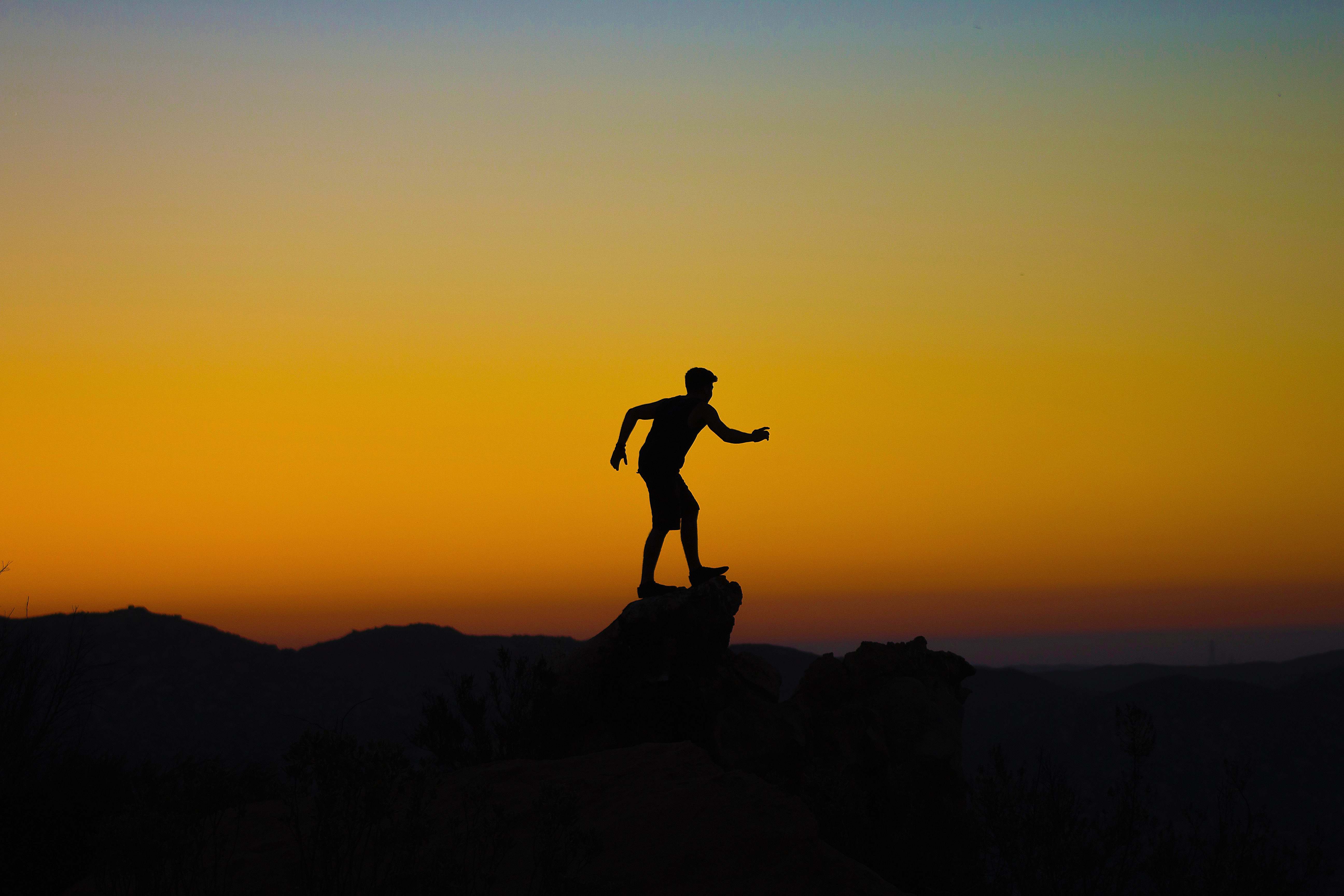 sunset silhouette photo of person on mountain cliff sunrise Image ...