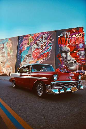 car red classic car parked beside wall with graffiti transportation