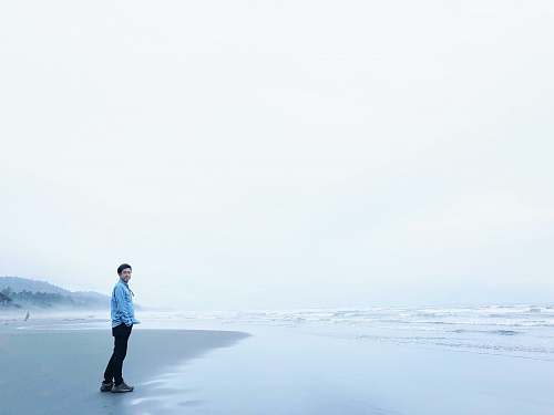 blue man standing at sea side during cloudy skies kalaloch beach