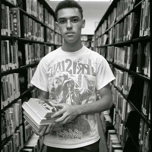 indoors man in white crew neck t-shirt holding book room