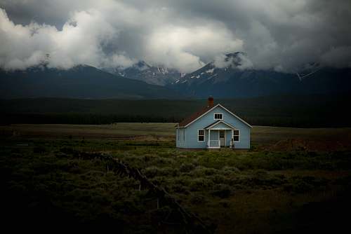 house house on grass field under gray sky cottage