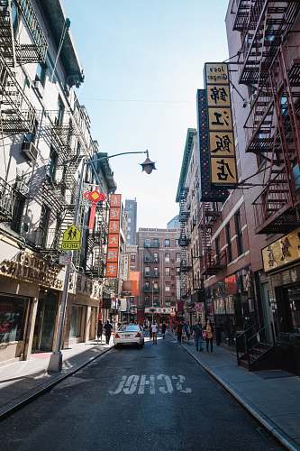 city people walking in between buildings road