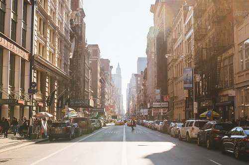 city person walking on road beside cars road