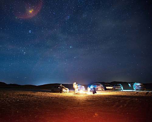 night lighted fire near car and dome tent during night time milky way