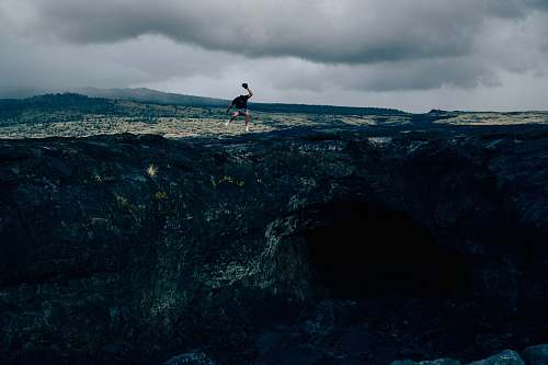 person man standing on rock formation during daytime man