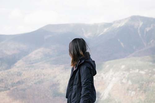 jacket person wearing black jacket leaning mountain during daytime apparel