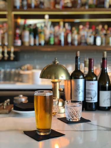 alcohol clear drinking glass beside wine bottle on table beverage