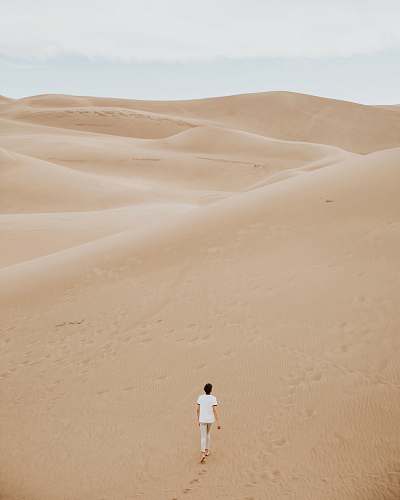 desert person walking on sand dune sand
