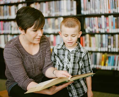 person boy in gray sweater beside boy in gray and white plaid dress shirt book