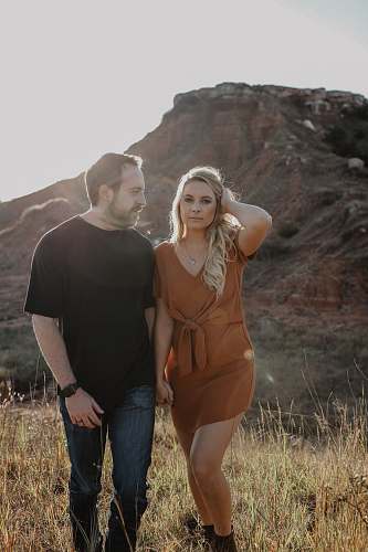 person man and woman holding hands on grass field during daytime people