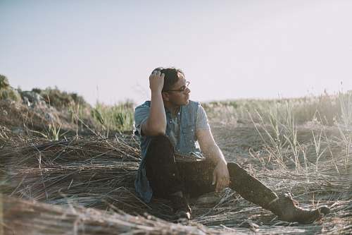 person man sitting on brown grass at daytime people