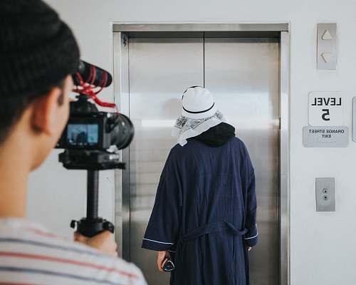 person person filming man standing near elevator inside room people