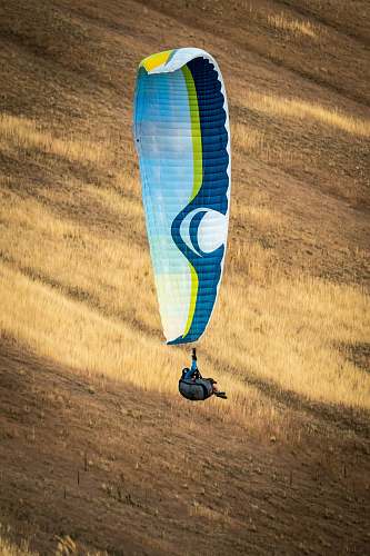 person person hanging on white and blue parachute adventure