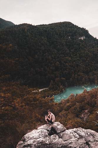 person photo of man sitting on rock formation people