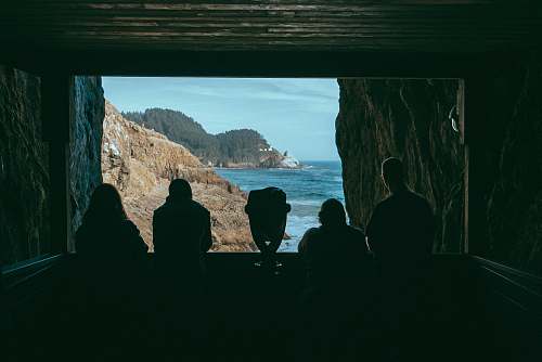 person silhouette of four people facing cliff near sea people