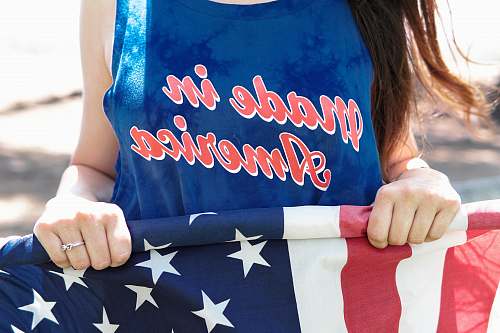 people woman in blue sleeveless top holding flag of America person