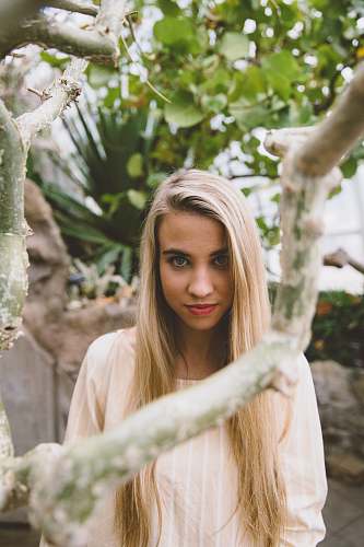 people woman wearing peach-colored scoop-neck top standing near green leafed tree person