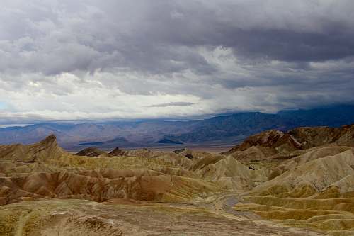 nature beige mountains under cloudy sky during daytime outdoors