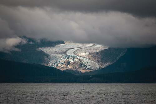 glacier body of water near mountains ice