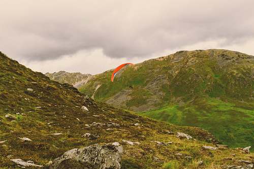 nature photo of person sky diving in between mountains alps